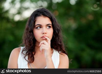 Pensive beautiful brunette girl relaxing in the park wiht many plants of background