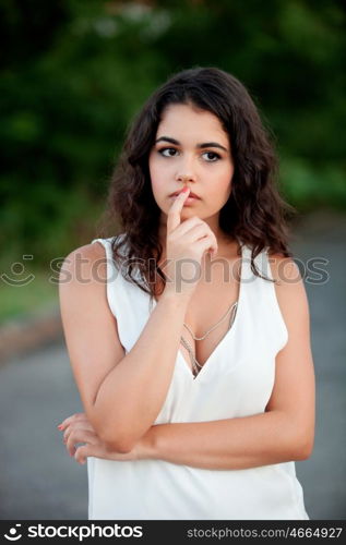 Pensive beautiful brunette girl relaxing in the park wiht many plants of background