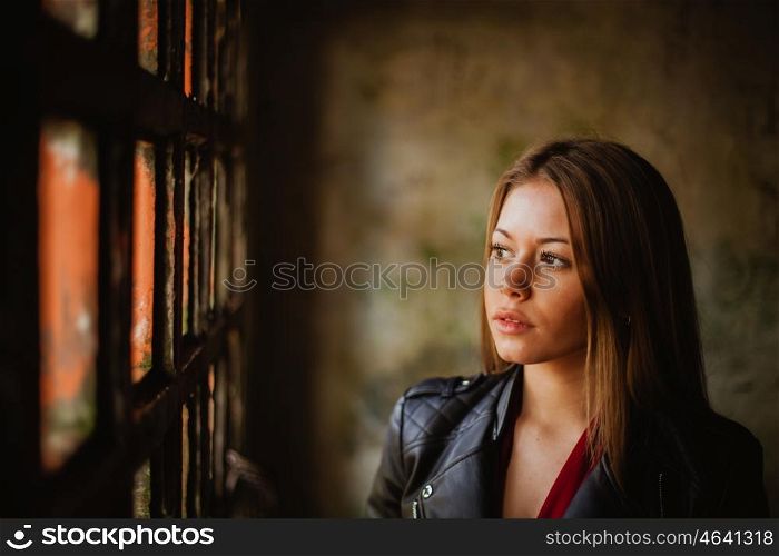 Pensive blonde woman next to a vintage windows