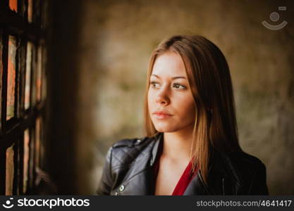 Pensive blonde woman next to a vintage windows