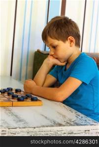 Pensive boy during a game of checkers