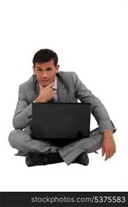 Pensive businessman sat on floor with laptop