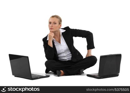 Pensive businesswoman sat with two laptops