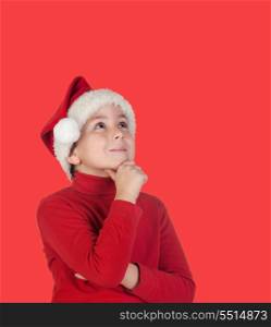 Pensive child with blond hair and Christmas hat isolated on blue background