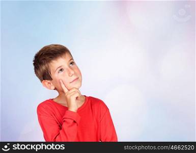 Pensive child with blond hair isolated on blue background