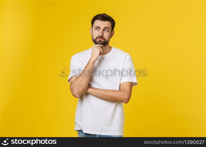 Pensive curious man looking up in thinking pose trying to make choice or decision isolated on yellow background. Pensive curious man looking up in thinking pose trying to make choice or decision isolated on yellow background.