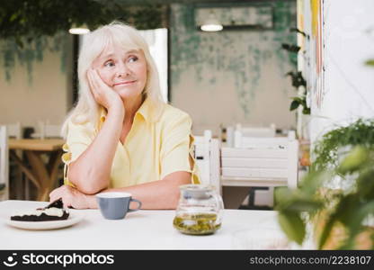 pensive elderly woman sitting table cafe