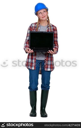 Pensive female builder holding laptop