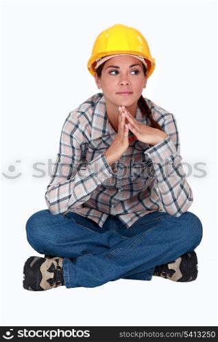 Pensive female builder sat cross-legged