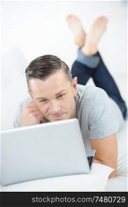 pensive guy lying on bed with laptop