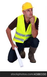 Pensive laborer crouching on white background