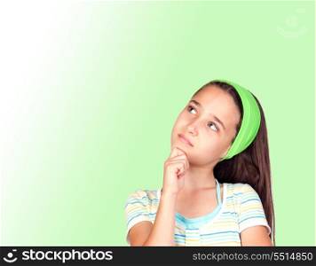 Pensive little girl with a green headband isolated on green background