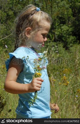 pensive little girl with flowers in a field