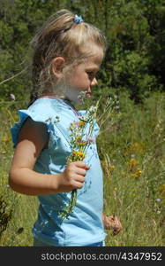 pensive little girl with flowers in a field