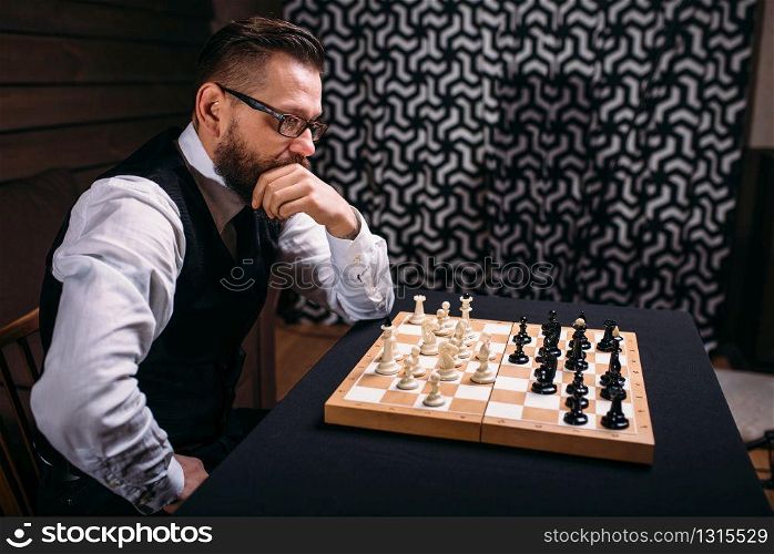 Pensive male chess player in glasses thinking about game strategy. Intelligence competition concept. Pensive chess player thinking about game strategy