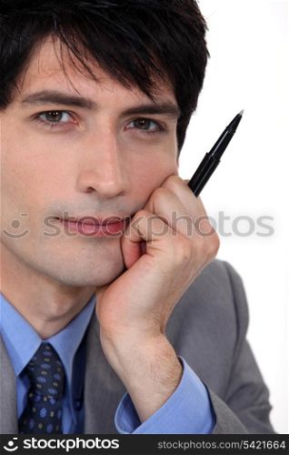 Pensive man holding pen to mo face