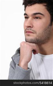 Pensive man stood touching chin with fist