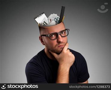 Pensive man with office details in the head over grey. Man with office equipment in the head