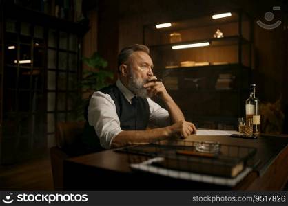 Pensive overwhelmed senior business man smoking cigar while sitting at work table with opened drink of alcohol in home office. Bad thoughts, professional burnout concept. Pensive senior business man smoking cigar while sitting at work table