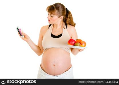 Pensive pregnant woman making choice between drugs and fruits isolated on white&#xA;
