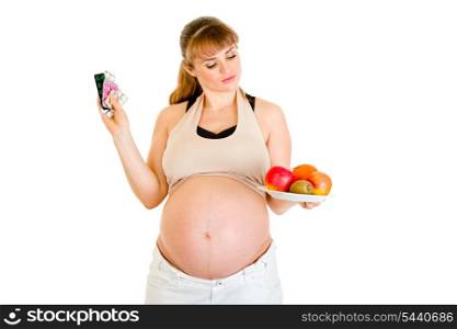 Pensive pregnant woman making choice between pills and fruits isolated on white&#xA;