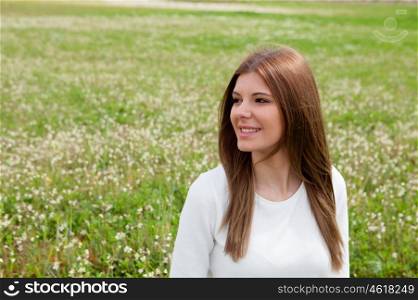 Pensive pretty woman at the meadow looking at the side surrounded flowers
