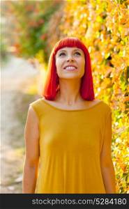 Pensive red haired woman in a park lit with a golden light looking up