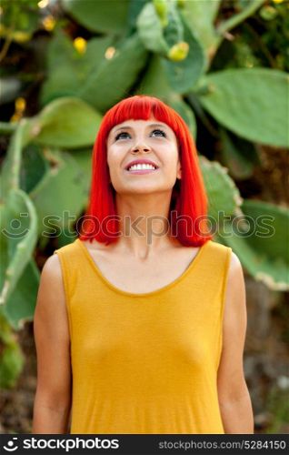 Pensive red haired woman in a park looking up
