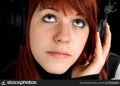 Pensive redhead girl listening to music and enjoying it (looking up, thinking). Studio shot.