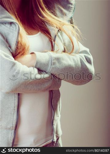 Pensive teenager girl crossing arms.. Closeup of rebellious teenager crossing arms wearing sweatshirt.