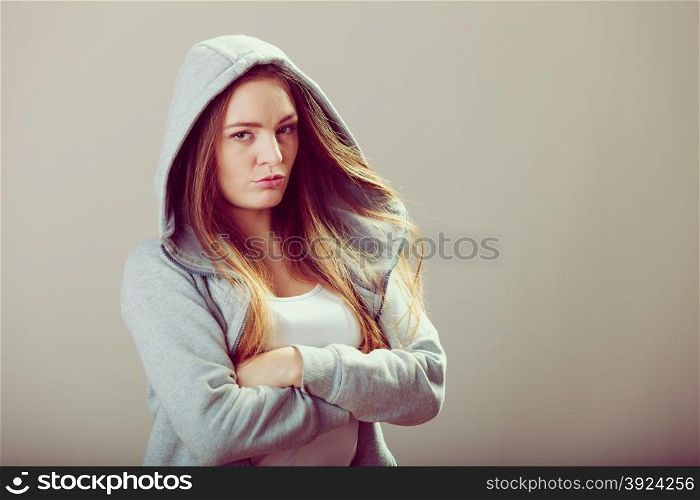 Pensive teenager girl in hood crossing arms.. Portrait of rebellious pensive thoughtful teenager crossing arms wearing hooded sweatshirt.