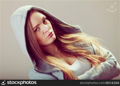 Pensive teenager girl in hood crossing arms.. Portrait of rebellious pensive thoughtful teenager crossing arms wearing hooded sweatshirt.