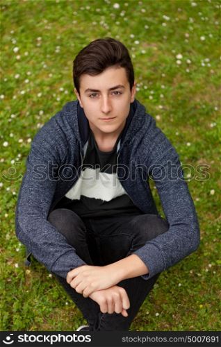 Pensive teenager guy with fifteen years old in a park