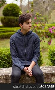 Pensive teenager guy with fifteen years old in a park