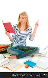 Pensive teenager sitting on floor among schoolbooks and studying isolated on white &#xA;
