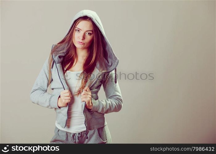 Pensive thoughtful teenager girl wearing sweatshirt with hood and white shirt. Teen fashion. Studio shot.