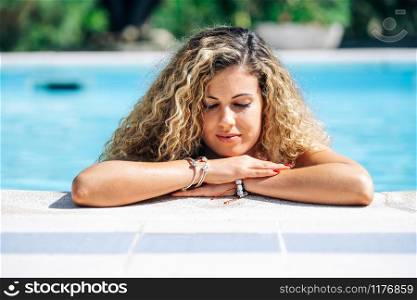 pensive woman at the edge of a pool. holiday concept
