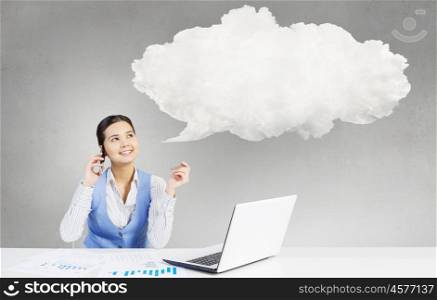 Pensive woman at work. Beautiful woman sitting at table talking on mobile phone and speech cloud above