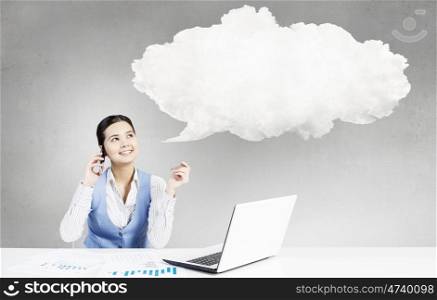 Pensive woman at work. Beautiful woman sitting at table talking on mobile phone and speech cloud above