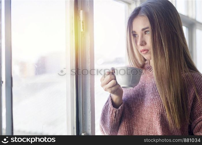 Pensive woman looking through a window