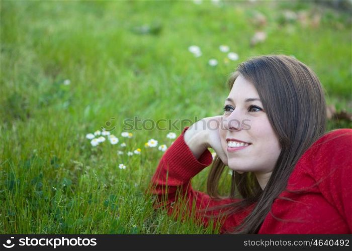 Pensive woman lying in the grass with lots of flowers around
