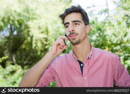 pensive young casual man on the phone, outdoor