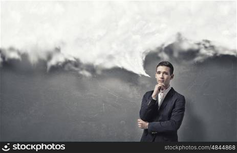 Pensive young man . Handsome young man in suit on concrete background looking in camera