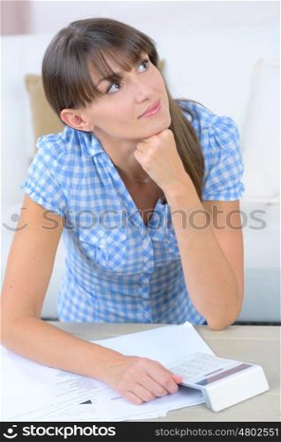 pensive young woman holding a calculator