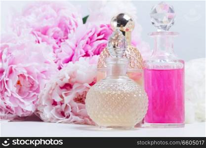 Peony essence oil and fragrance water in glass vials and fresh peony flowers. Peony essence vials