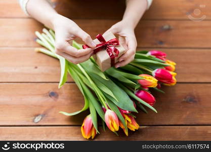 peoople, holidays and greeting concept - close up of woman holding gift box and tulip flowers