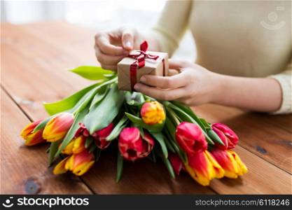 peoople, holidays and greeting concept - close up of woman holding gift box and tulip flowers