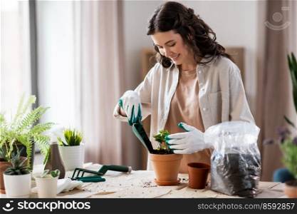peop≤, gardening and housework concept - happy woman in gloves planting pot flowers at home. happy woman planting pot flowers at home