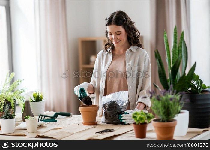 peop≤, gardening and housework concept - happy woman in gloves planting pot flowers at home. happy woman planting pot flowers at home