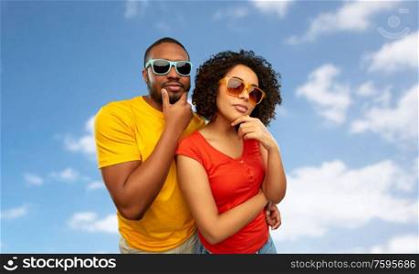 people, accessories and summer concept - african american couple in sunglasses thinking over grey background. african couple in sunglasses thinking